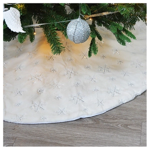 Detail of white plush Christmas tree skirt featuring silver embroidered snowflake patterns