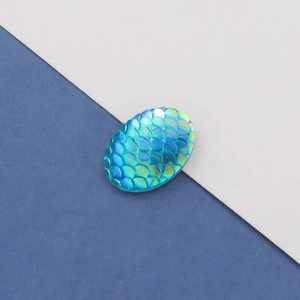 Macro shot of oval mermaid fish scale resin cabochons in iridescent AB blue-green color