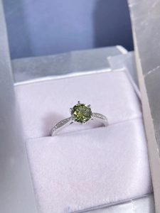 Detail view of round green moissanite set in a six-prong silver engagement ring