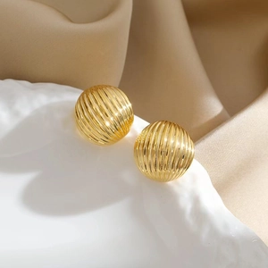 Macro shot of gold-tone spherical earrings with fine textured stripe detailing