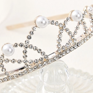 Close-up of silver crown headband featuring sparkling rhinestones and white pearls