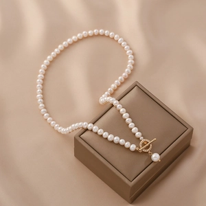 Elegant natural freshwater pearl necklace with golden OT toggle clasp on a jewelry box