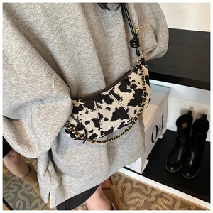 Dettaglio borsa hobo con stampa mucca, catena dorata e tracolla regolabile in pelle nera