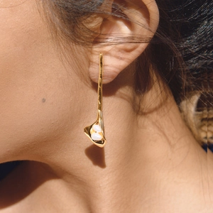 Elegant gold calla lily drop earrings with freshwater pearls worn by a female model