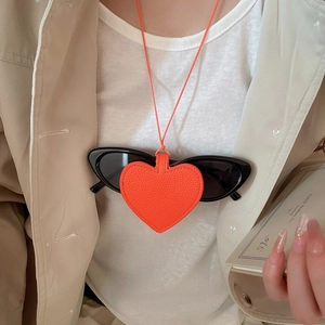 Detail of a heart-shaped orange leather eyewear holder showing secure sunglasses attachment