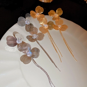Détail de boucles d'oreilles fleur à pompons dorées et argentées avec zircons brillants