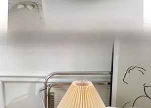 Detail of a pleated cream lampshade with vintage metal stand and minimalist decor