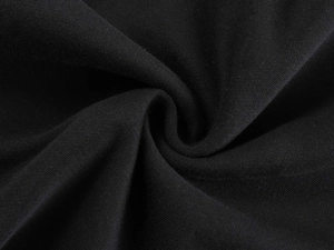 Macro view of soft black cotton knit fabric showing flexible texture and drape