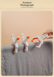 Close-up of white windproof quilt clips with orange non-slip pads holding a blanket