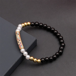 Detail of beaded bracelet with black polished beads and colorful zircon gold tube