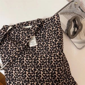 Close-up of leopard print canvas tote bag with white woven label on white surface