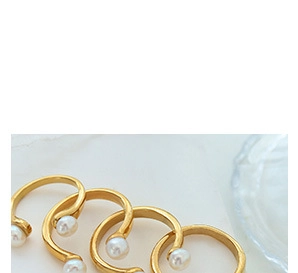 Vue détaillée de quatre bagues C dorées minimalistes ornées de perles blanches