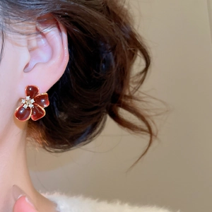 Macro detail of a 18K gold plated red enamel flower earring with sparkling zircons