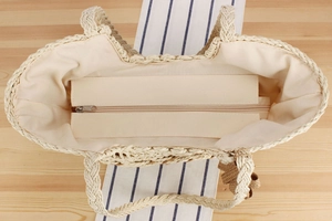 Detail view of woven straw tote bag featuring secure zipper closure and cotton lining inside