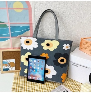 Detail of grey canvas tote bag with large floral print in lifestyle studio setting