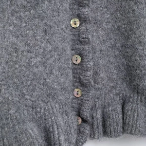 Gray knitted cardigan featuring ruffled trim, shell buttons and soft mohair texture