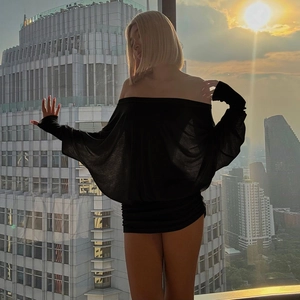 Close-up of black off-shoulder mini dress with ruched details on a sunset city background