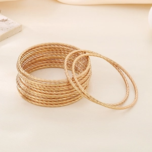 Close-up of golden multi-layer twisted rope bangles with detailed stainless steel texture