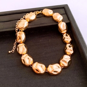 Macro shot of gold irregular pebble metal bracelet on black jewelry tray