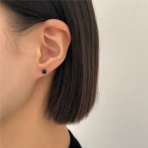 Close-up of minimalist black onyx round stud earrings worn on the earlobe