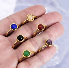 Hand wearing six gold titanium steel rings with assorted colorful round gemstones