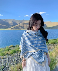 Detail of blue and beige houndstooth scarf texture against a scenic lake background