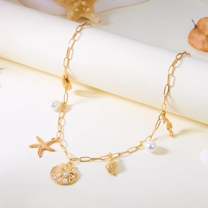 Gold paperclip necklace featuring sea shell, starfish, and pearl charms on a white pedestal