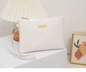 Detailed view of white crocodile pattern faux leather handbag with gold metal zippers