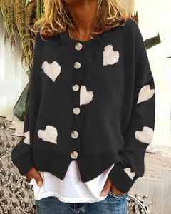 Detail of single-breasted black knit cardigan with white heart jacquard pattern