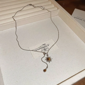 Macro shot of silver sun pendant with brown tiger eye stone on beige jewelry tray