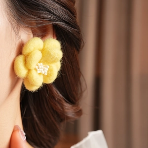 Vue détaillée latérale des boucles d'oreilles fleurs en feutre jaune fait main