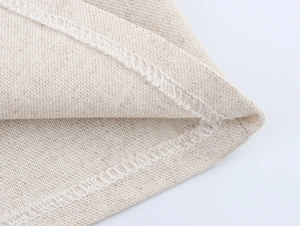 Dettaglio macro del tessuto in lino beige e cuciture taglia-cuci bianche su gilet e pantaloni
