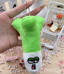 Close-up of a plush green onion keychain with an embroidered face and silver ball chain
