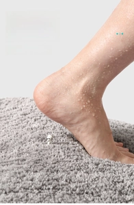 Close-up of wet foot on plush grey absorbent microfiber bath mat with high pile texture
