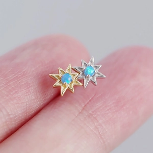 Dettaglio macro di orecchini a forma di stella con intarsio in opale blu tra le dita
