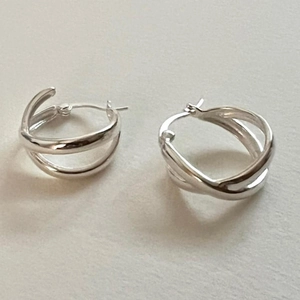 Close-up of silver hoop earrings with an intertwined triple line design in sterling silver