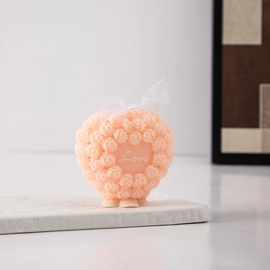 Macro shot of pink heart-shaped candle with rose textures and a Love engraving