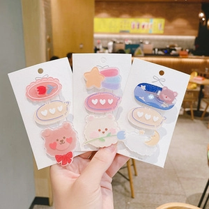 Close-up of cute acrylic cream-style bear and heart hair clips on white cardboards