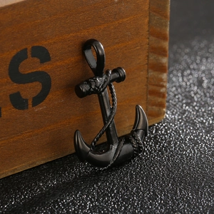 Close-up of black anchor pendant with rope details leaning on a vintage wooden box
