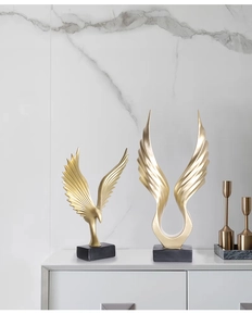 Close-up of golden eagle sculptures with black marble bases on white luxury cabinet