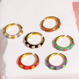 Set of six colorful enamel butterfly open rings with gold plating on a stone background
