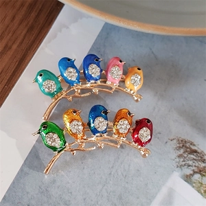 Close-up of colorful enamel bird brooches with sparkling rhinestones on golden branches