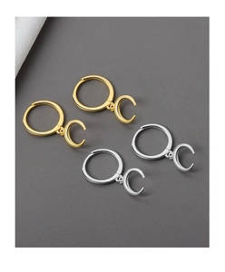 Polished gold and silver crescent moon hoop earrings on a dark textured background