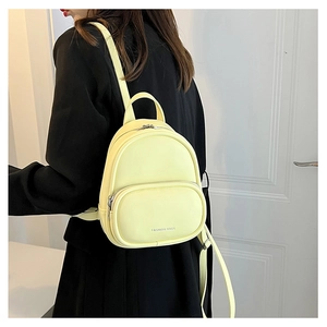 Detailed back view of a mini cream yellow PU leather backpack worn over a black blazer