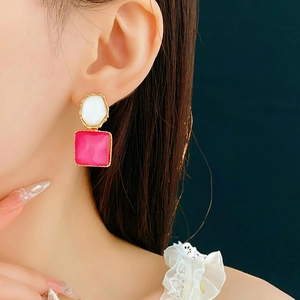 Detailaufnahme von asymmetrischen Ohrringen mit rosa und weißen Edelsteinen an einem Model