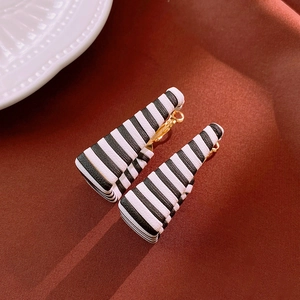 Detailed view of geometric black and white striped leaf earrings with gold metal accents