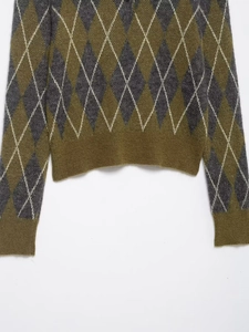 Detailed view of the diamond argyle knit pattern and ribbed cuffs on the polo shirt
