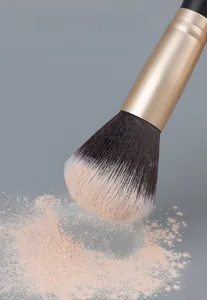Macro detail of professional makeup brush picking up powder with dual-tone soft bristles