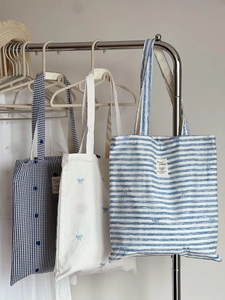 Detailed embroidery of blue flowers and bows on striped cotton canvas tote bags