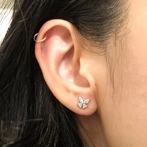 Detail shot of a silver bow earring with cubic zirconia and a matching silver cartilage cuff